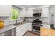 Kitchen featuring white cabinets, stainless steel appliances, and mosaic tile backsplash at 213 Beechtree Dr, Cary, NC 27513