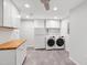 Bright laundry room with washer, dryer, cabinets, butcher block countertop, and gray tile floor at 213 Beechtree Dr, Cary, NC 27513