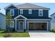Charming two-story home with blue siding, an open garage, a manicured lawn, and decorative landscaping at 2218 Cherry Creek Rd, Haw River, NC 27258