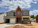 New two-story home with a brick accent wall, two-car garage, and green siding against a blue sky at 2324 Eagle Shot Ct # 19, Fuquay Varina, NC 27526