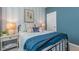 Well-lit bedroom with unique blue wallpaper and a bed with a striped comforter and a blue blanket at 2736 Luxborough Ln, Mebane, NC 27302