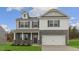 Two-story home featuring a two-car garage, brick facade, and a welcoming front porch with classic architectural style at 2739 Luxborough Ln, Mebane, NC 27302
