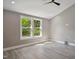 Bright bedroom featuring hardwood floors, a ceiling fan, neutral walls, and a large window with wooded views at 313 Crown Oaks Dr, Raleigh, NC 27615