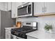 Close up of the kitchen features including stainless steel microwave and gas range with custom tile backsplash at 3715 Rosebush Dr, Zebulon, NC 27597