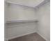 Walk-in closet featuring white shelving and neutral colored carpet at 4936 Liverpool Ln, Raleigh, NC 27604