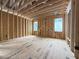 New home bedroom under construction featuring wooden framing, multiple windows, and plywood flooring materials at 516 Transylvania Ave, Raleigh, NC 27609