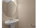 This powder room has a pedestal sink with a round mirror and neutral wall color at 5329 Big Bass Dr, Raleigh, NC 27610