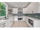 Bright kitchen with white cabinets, stainless steel appliances, light wood floors, and blue tiled backsplash at 621 Bon Air Ave, Durham, NC 27704