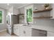 Modern kitchen featuring a stainless steel refrigerator, white cabinets, and floating wooden shelves at 621 Bon Air Ave, Durham, NC 27704