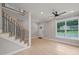Bright living room with hardwood floors, a modern ceiling fan, and staircase with contemporary black railings at 621 Bon Air Ave, Durham, NC 27704