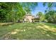 Large, grassy backyard with mature trees, deck, basketball court, and plenty of space for recreation at 704 N Orange Ave, Dunn, NC 28334