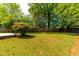 Large backyard featuring a wood fence, mature trees and a well-maintained lawn at 705 Hartford Rd, Raleigh, NC 27610