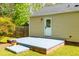 Back of house with patio, door to the backyard, and lush greenery, plus flowering potted plants at 705 Hartford Rd, Raleigh, NC 27610