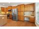 A modern kitchen featuring stainless steel appliances, wood cabinetry, countertop workspace, and tiled backsplash at 803 Footbridge Pl, Cary, NC 27519