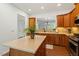 Bright kitchen featuring an island, wooden cabinets, and an open view into the living room at 803 Footbridge Pl, Cary, NC 27519