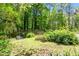 A secluded and picturesque backyard featuring a green space, mature trees, and seating at 803 Old Mill Rd, Chapel Hill, NC 27514