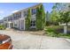 A tan townhouse with dark shutters, a covered front porch, landscaping, and a concrete driveway at 8520 Quarton Dr, Raleigh, NC 27616