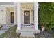 A well-kept townhome entrance featuring a covered porch, brown door with a wreath, and green landscaping at 8520 Quarton Dr, Raleigh, NC 27616