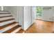 Hardwood staircase and floors in the entryway, near a closet and glass-paneled door to the outside at 905 Cindy St, Cary, NC 27511