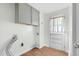 Utility room featuring overhead gray cabinets, wood floor, and connections for a washer and dryer at 905 Cindy St, Cary, NC 27511