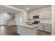 Spacious kitchen featuring a granite island, gray cabinets, stainless steel appliances, and wood floors at 112 Global Ave, Fuquay Varina, NC 27526