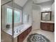 Bright bathroom featuring a glass-enclosed shower, soaking tub, and vanity with dark wood cabinets at 113 Chesterfield Dr, Cary, NC 27513