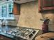 Kitchen stovetop with granite countertops and travertine backsplash at 113 Chesterfield Dr, Cary, NC 27513