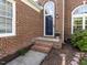 Inviting entryway with classic brick steps and decorative plants. Arched windows on either side at 117 Whitehaven Ln, Cary, NC 27519