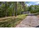 View of the home's exterior featuring a long driveway and surrounded by lush trees at 120 King Charles Rd, Hillsborough, NC 27278