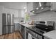 Modern kitchen featuring stainless steel appliances, quartz countertops, white cabinets, and wood-look flooring at 120 King Charles Rd, Hillsborough, NC 27278