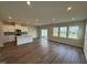 Open-concept living room and kitchen area with hardwood floors and ample natural light from the windows at 1214 Tredenham Way, Durham, NC 27703