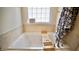 A soaking tub set in a tiled bath with a bamboo bath tray and a bright window for natural light at 123 Charndon Way, Fuquay Varina, NC 27526