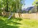 Large grassy backyard featuring play equipment and a wood fence at 1408 Bridgeport Dr, Raleigh, NC 27615