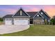 Charming home with a three-car garage, stone accents, and a well-manicured lawn at sunset at 194 Spring Hill Church Rd, Lillington, NC 27546