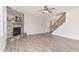 Living room featuring stone fireplace, ceiling fan, and staircase with iron spindles at 194 Spring Hill Church Rd, Lillington, NC 27546