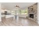 Open-concept living room with a stone fireplace, ceiling fan, and large windows providing ample natural light at 194 Spring Hill Church Rd, Lillington, NC 27546