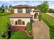 Attractive stucco house with a tile roof, lush landscaping, and a brick driveway at 20 Al Aqua Dr, Durham, NC 27707