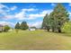 Expansive backyard with lush green lawn, mature trees, and a charming storage shed at 208 E Harrington Ave, Broadway, NC 27505