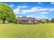 Expansive backyard with a well-maintained lawn, mature trees, and charming landscape features at 208 E Harrington Ave, Broadway, NC 27505