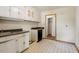 Outdated kitchen featuring a black dishwasher, white cabinets, and retro-style flooring at 2343 Derby Dr, Raleigh, NC 27610