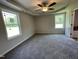A bedroom with carpet flooring, tray ceiling with fan, and windows at 261 Phil Jack Rd, Dunn, NC 28334