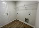 Functional laundry room with laminate floors, utility connections, and a wire shelf for organizing cleaning supplies at 299 Phil Jack Rd, Dunn, NC 28334
