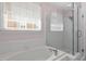 Bathroom featuring a tub, shower with glass doors, and a window offering natural light at 30038 Village Park Dr, Chapel Hill, NC 27517