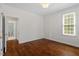 Empty bedroom with hardwood floors, white walls, and a window; bathroom door visible at 30038 Village Park Dr, Chapel Hill, NC 27517
