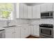 Kitchen featuring white cabinets, marble backsplash, and stainless steel microwave and gas range at 30038 Village Park Dr, Chapel Hill, NC 27517
