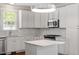 Kitchen featuring white cabinets, marble backsplash, island, and stainless steel microwave and gas range at 30038 Village Park Dr, Chapel Hill, NC 27517