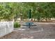 Scenic picnic area featuring a green picnic table, umbrella, and white picket fence in a lush, tree-filled community space at 30038 Village Park Dr, Chapel Hill, NC 27517