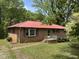 Cozy brick home with a red metal roof, charming shutters, and a well-maintained front yard at 311 N Nash St, Hillsborough, NC 27278