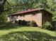 Quaint brick home featuring a red metal roof, traditional shutters, and mature landscaping at 311 N Nash St, Hillsborough, NC 27278