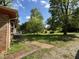 View of the front yard with mature trees and landscaping, and a traditional brick home at 311 N Nash St, Hillsborough, NC 27278